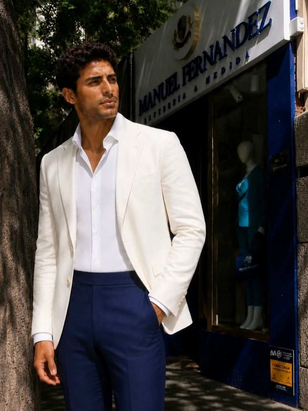 Americana blanca de lino y pantalón azul frente al escaparate de la sastrería en Jorge Juan