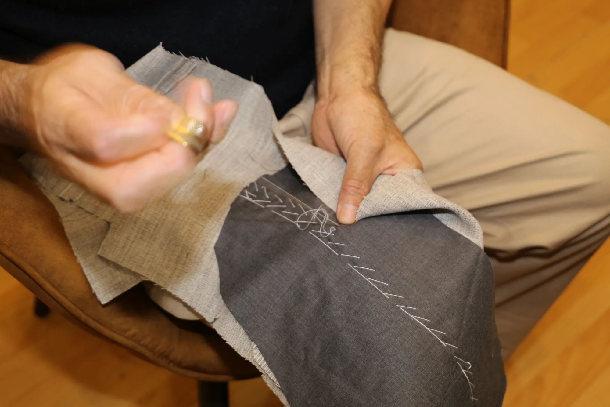 Canvas being pad-stitched by hand onto the cloth, thimble in place