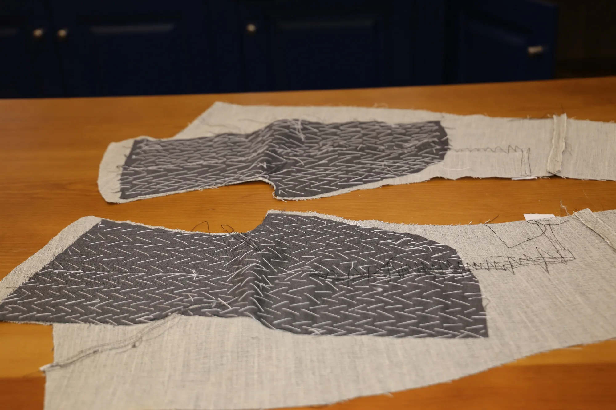 Entretelas de pecho picadas a mano con hilo blanco, sobre la mesa de corte