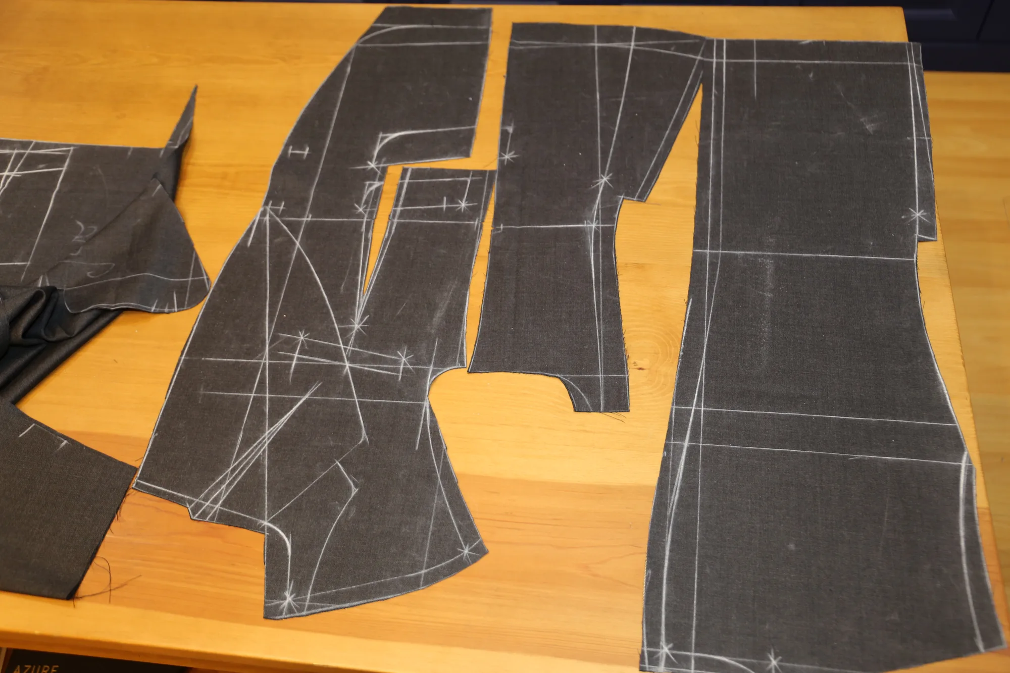 Cut cloth pieces on the cutting table, chalk marks still visible