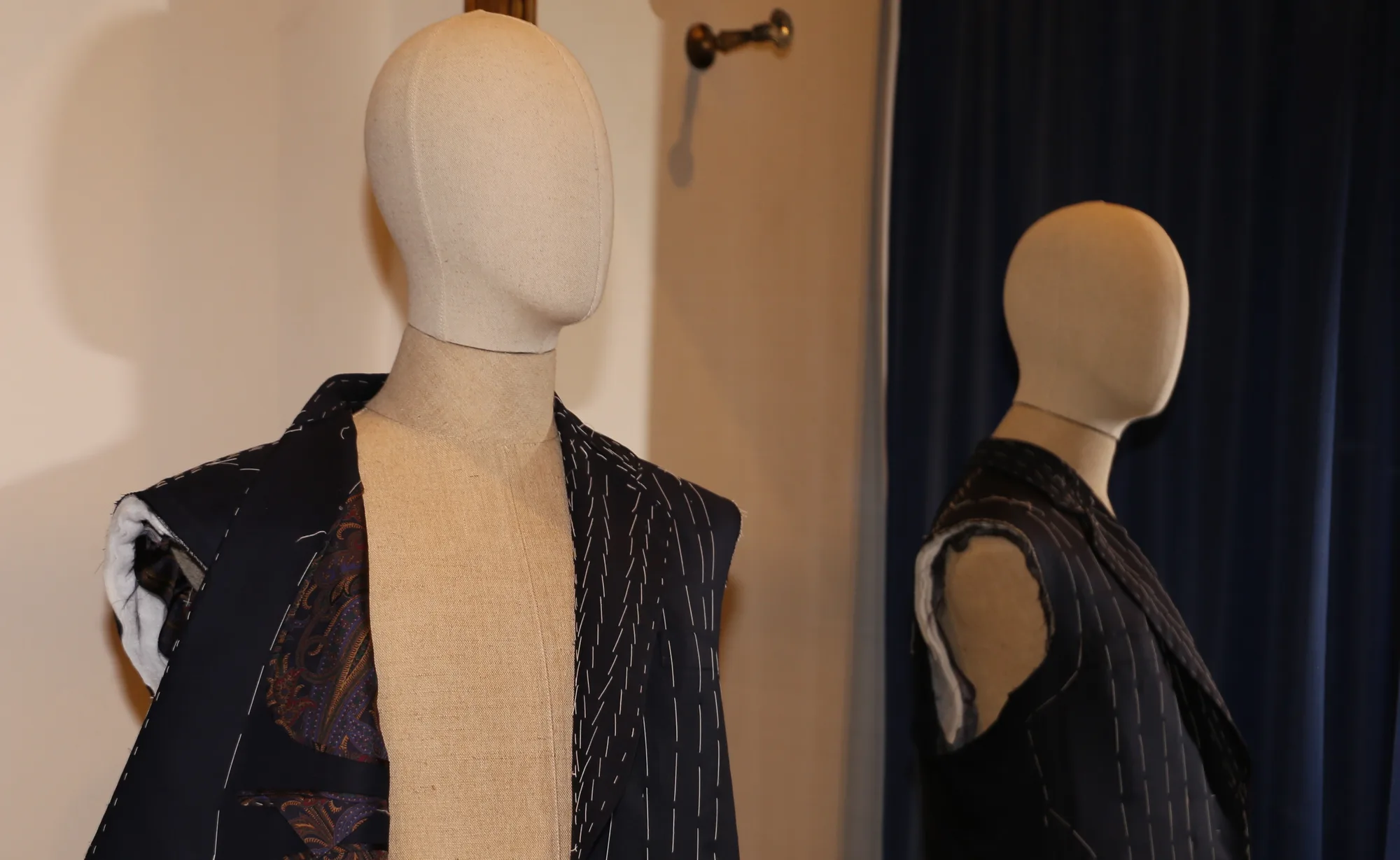 Chaqueta hilvanada sobre maniquí, con las puntadas provisionales blancas y el forro a la vista