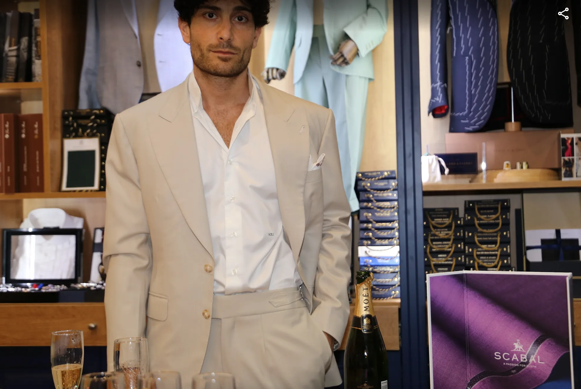 Traje de novio en tono beige, con camisa blanca de cuello abierto, en el showroom